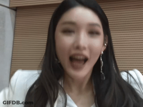 A Woman With Long Black Hair And Earrings Is Making A Funny Face GIF