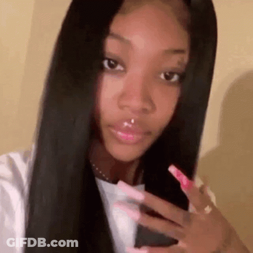 A Woman With Long Black Hair And Long Pink Nails Is Taking A Selfie . GIF