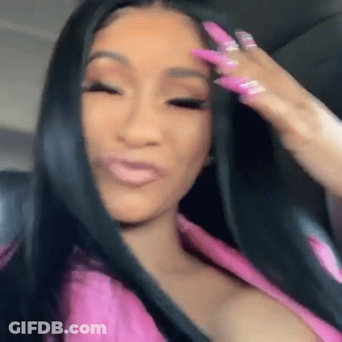 A Woman With Long Black Hair And Pink Nails Is Making A Funny Face While Sitting In A Car . GIF