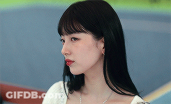 A Woman With Long Black Hair And Red Lipstick Is Wearing A White Top And A Necklace . GIF