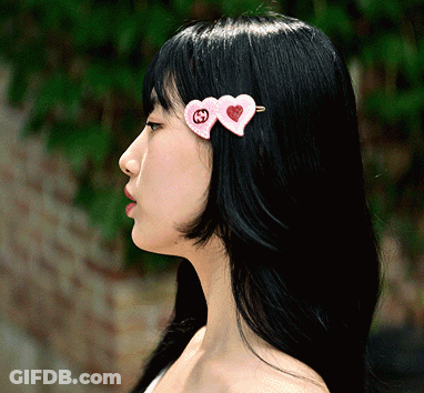 A Woman With Long Black Hair Has Two Pink Hearts On Her Hair GIF