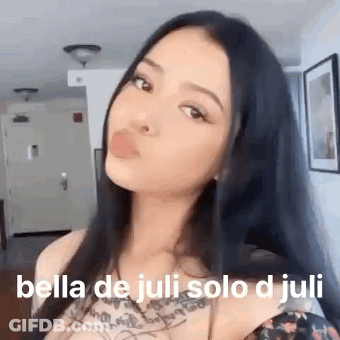 A Woman With Long Black Hair Is Blowing A Bubble With Her Mouth . GIF