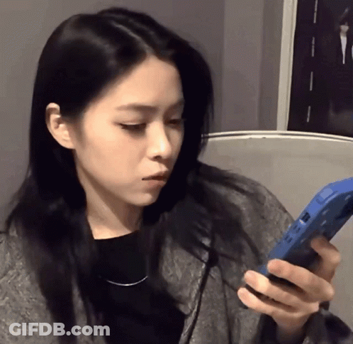 A Woman With Long Black Hair Is Holding A Blue Phone GIF