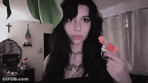 A Woman With Long Black Hair Is Holding A Small Toy Gun GIF