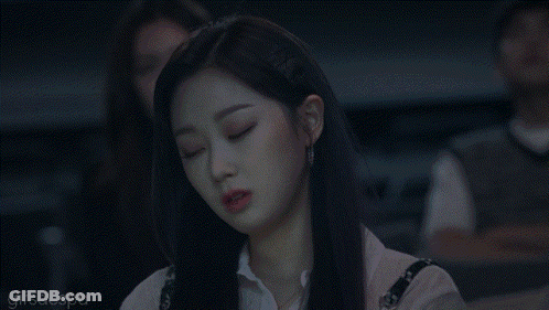 A Woman With Long Black Hair Is Sitting In A Dark Room And Looking At Something . GIF