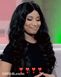 A Woman With Long Black Hair Is Sitting On A Couch With Hearts Around Her . GIF