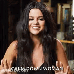A Woman With Long Black Hair Is Smiling And Giving A Peace Sign . GIF