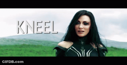 A Woman With Long Black Hair Is Standing In A Field With The Word Kneel Behind Her GIF