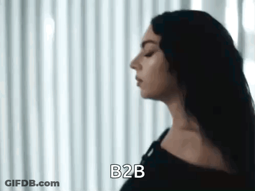 A Woman With Long Black Hair Is Standing In Front Of A White Curtain And Says B2b . GIF