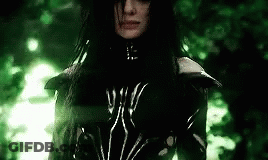 A Woman With Long Black Hair Is Wearing A Black And White Outfit . GIF