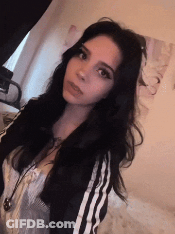A Woman With Long Black Hair Is Wearing A Black And White Striped Jacket GIF