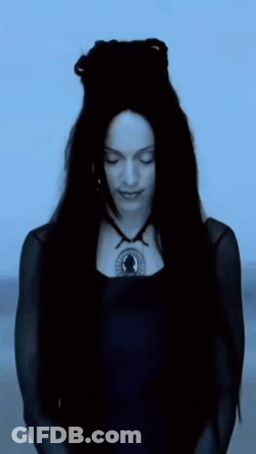 A Woman With Long Black Hair Is Wearing A Black Dress And A Black Necklace GIF