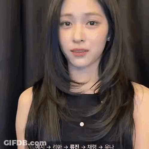 A Woman With Long Black Hair Is Wearing A Black Dress And Earrings . GIF