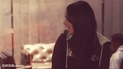 A Woman With Long Black Hair Is Wearing A Black Hoodie And Laughing . GIF