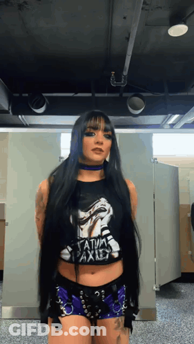 A Woman With Long Black Hair Is Wearing A Black Shirt That Says " Satanic Axis " GIF