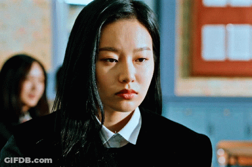 A Woman With Long Black Hair Is Wearing A Black Sweater And A White Shirt GIF