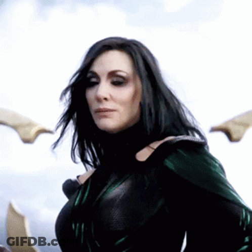 A Woman With Long Black Hair Is Wearing A Green Costume . GIF