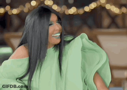 A Woman With Long Black Hair Is Wearing A Green Off The Shoulder Top GIF