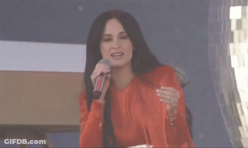 A Woman With Long Black Hair Is Wearing A Red Fringed Dress GIF