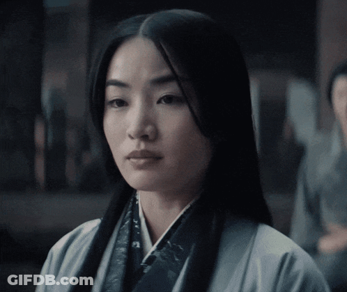 A Woman With Long Black Hair Is Wearing A White Jacket GIF