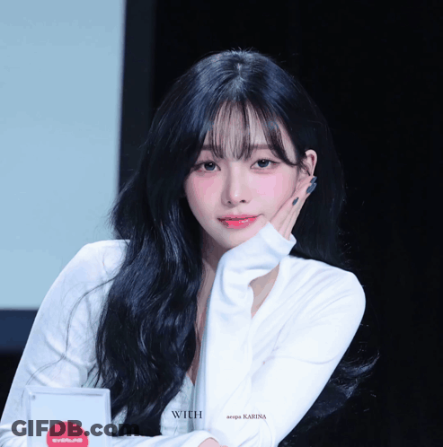A Woman With Long Black Hair Is Wearing A White Shirt That Says Karina GIF