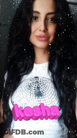 A Woman With Long Black Hair Is Wearing A White Shirt With The Word Kesha On It GIF