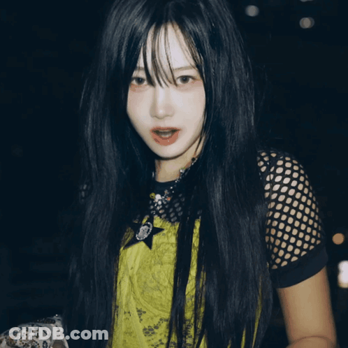 A Woman With Long Black Hair Is Wearing A Yellow Shirt With A Star On The Front GIF