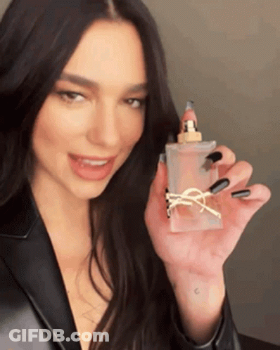 A Woman With Long Black Nails Is Holding A Bottle Of Perfume In Her Hand . GIF