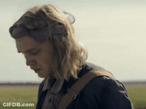 A Woman With Long Blonde Hair And A Brown Backpack Looks Down GIF