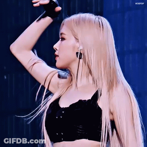 A Woman With Long Blonde Hair And A Tattoo On Her Arm Is Wearing A Black Top And Earrings . GIF