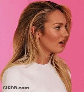 A Woman With Long Blonde Hair And A White Shirt Is Making A Funny Face . GIF