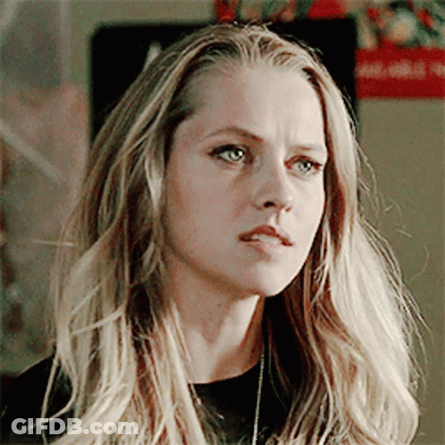 A Woman With Long Blonde Hair And Blue Eyes Is Wearing A Black Shirt GIF