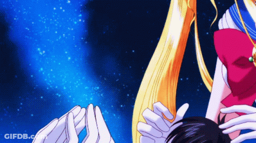 A Woman With Long Blonde Hair Is Holding A Man 'S Head GIF