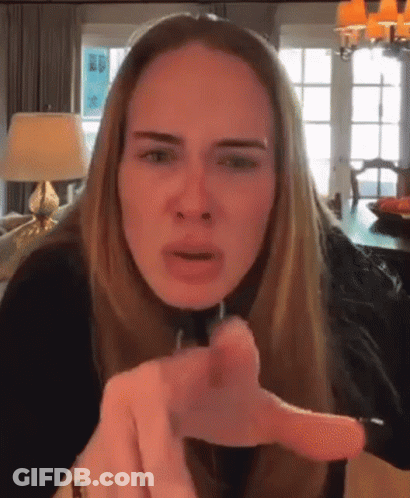 A Woman With Long Blonde Hair Is Pointing At The Camera . GIF