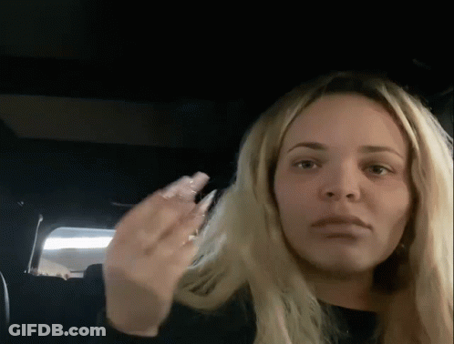 A Woman With Long Blonde Hair Is Sitting In The Back Seat Of A Car And Making A Funny Face . GIF