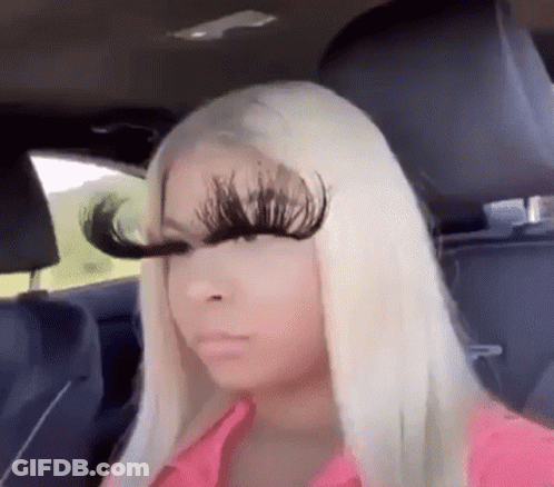 A Woman With Long Blonde Hair Is Sitting In The Back Seat Of A Car With A Pair Of Fake Eyelashes On Her Face . GIF
