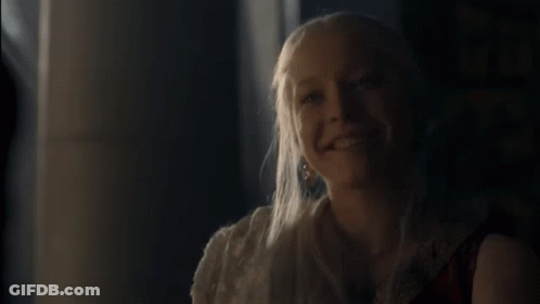 A Woman With Long Blonde Hair Is Smiling And Looking At The Camera . GIF