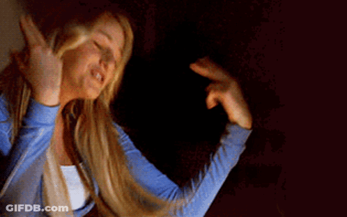 A Woman With Long Blonde Hair Is Smiling And Making A Peace Sign GIF