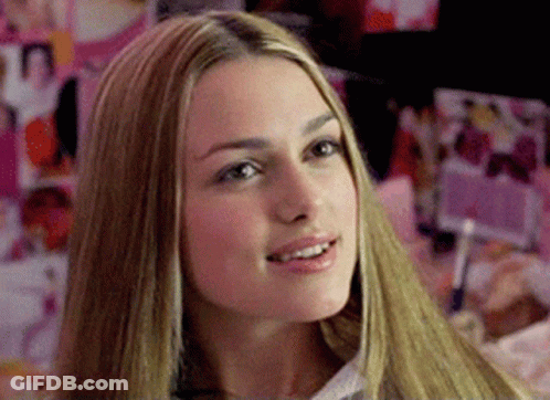 A Woman With Long Blonde Hair Is Smiling In Front Of A Wall Of Pictures GIF