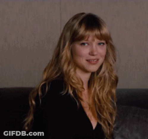 A Woman With Long Blonde Hair Is Smiling While Wearing A Black Top GIF