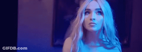 A Woman With Long Blonde Hair Is Standing In A Dark Room With Blue Lights . GIF