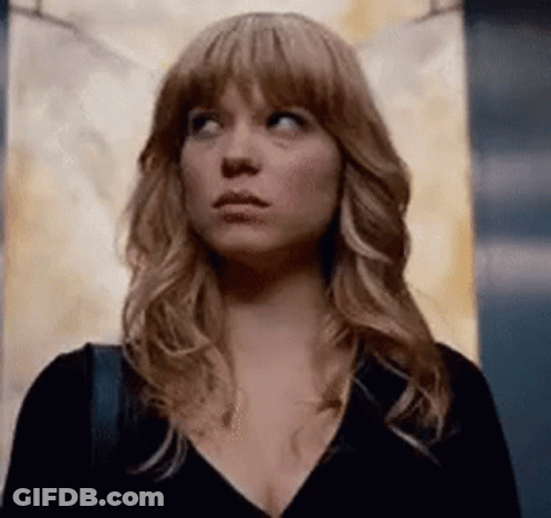 A Woman With Long Blonde Hair Is Standing In An Elevator Looking Up . GIF