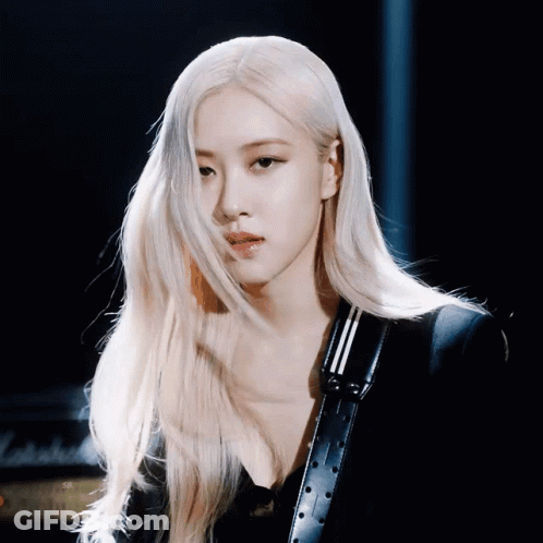 A Woman With Long Blonde Hair Is Wearing A Black Jacket And A Black Belt GIF