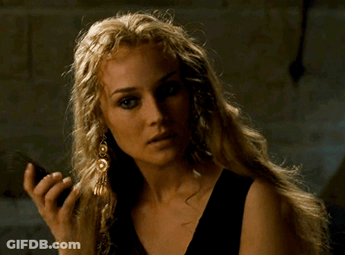 A Woman With Long Blonde Hair Is Wearing A Black Top And Earrings GIF