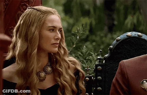 A Woman With Long Blonde Hair Is Wearing A Necklace And Sitting In A Chair . GIF