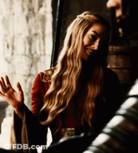 A Woman With Long Blonde Hair Is Wearing A Red Top And A Belt With The Letter S On It GIF