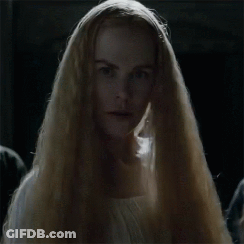 A Woman With Long Blonde Hair Is Wearing A White Dress And A Veil . GIF