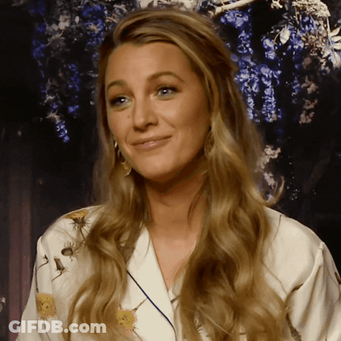 A Woman With Long Blonde Hair Is Wearing A White Robe With Flowers On It GIF