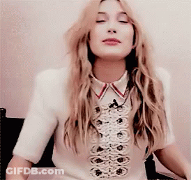 A Woman With Long Blonde Hair Is Wearing A White Shirt With A Red Collar GIF