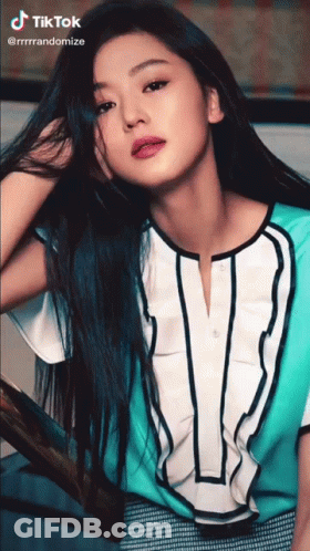 A Woman With Long Blue Hair Is Wearing A Blue And White Shirt With The Letter V On It GIF